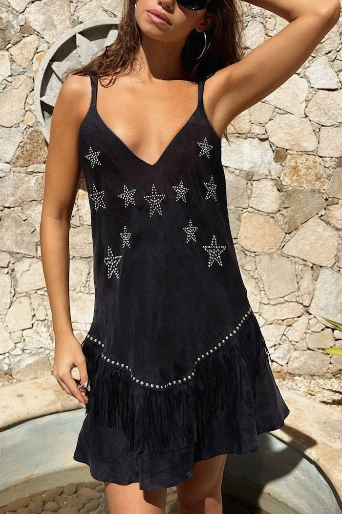 Woman wearing a black dress with star patterns against a stone wall.