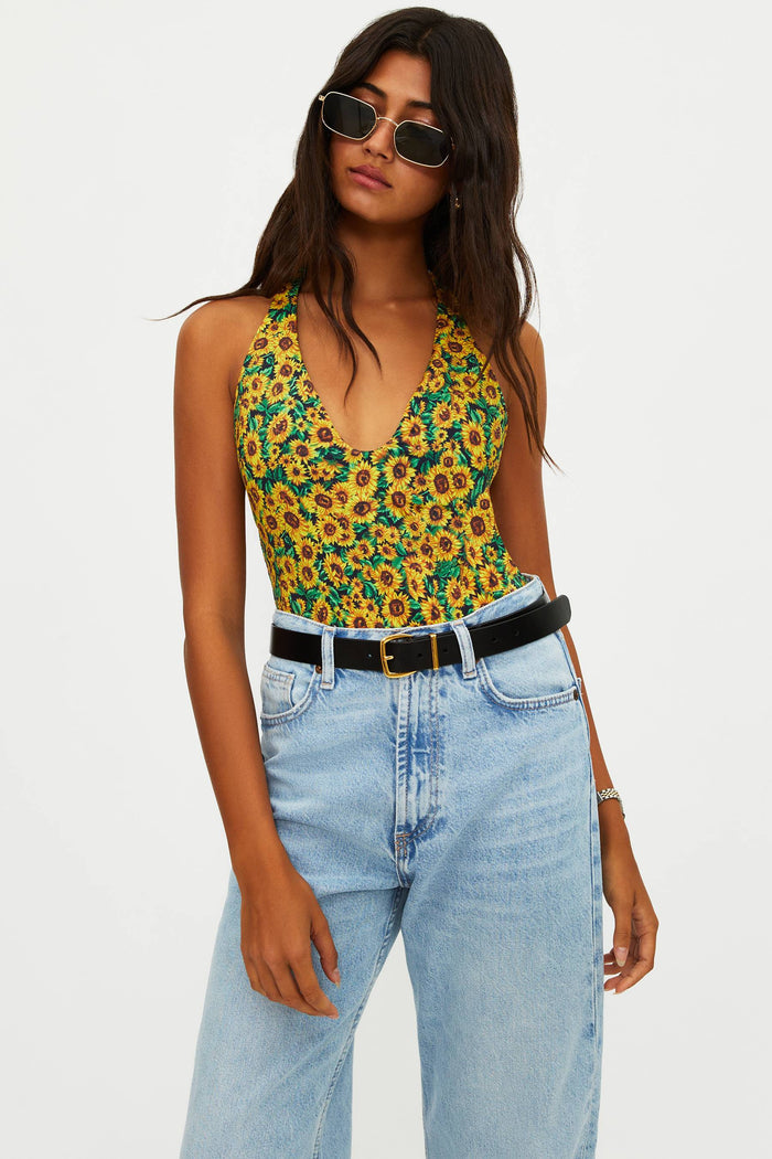 Woman wearing a floral top and jeans with sunglasses on a white background