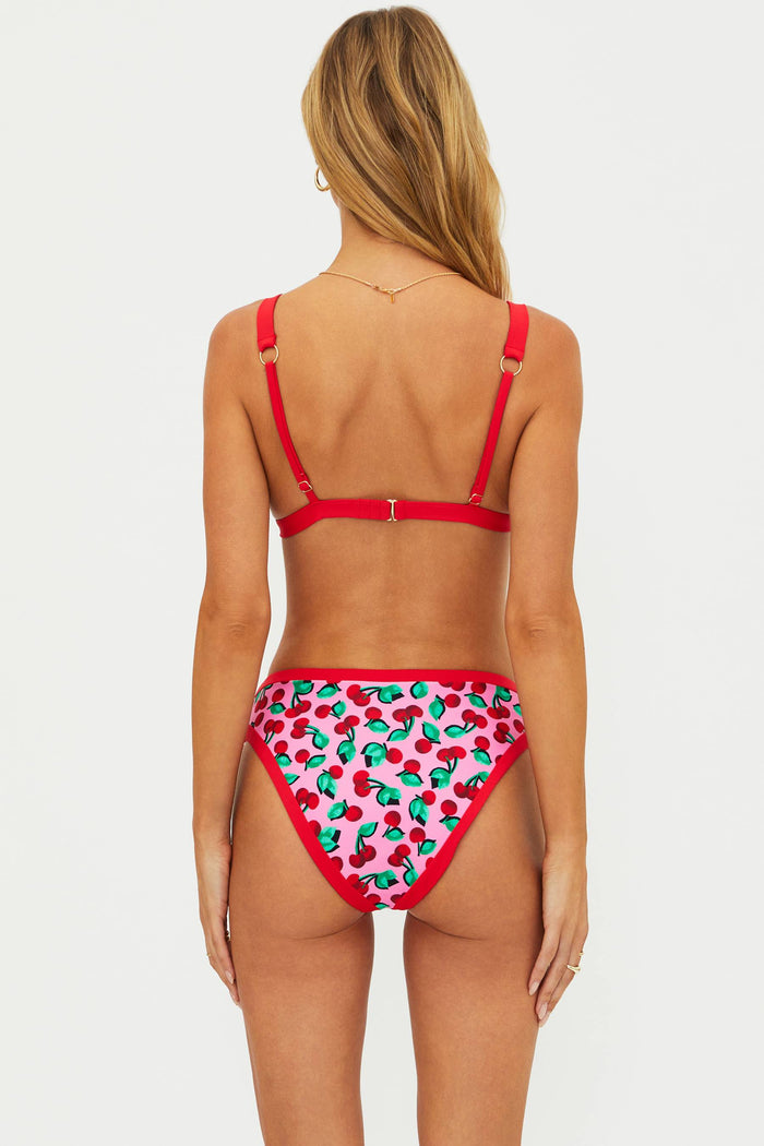 Woman wearing a red bikini with cherry pattern on a white background