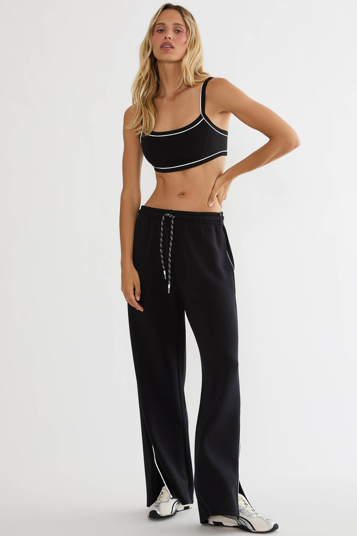Black track pants with white detailing on the side with slits in the hem.
