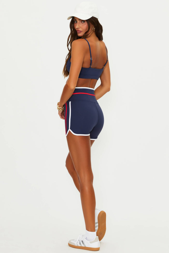 Woman wearing a navy sports bra and shorts set on a white background