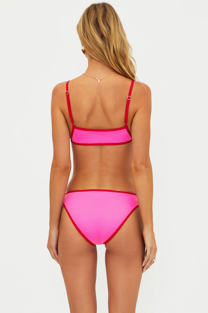 Woman wearing a pink bikini with red accents on a white background