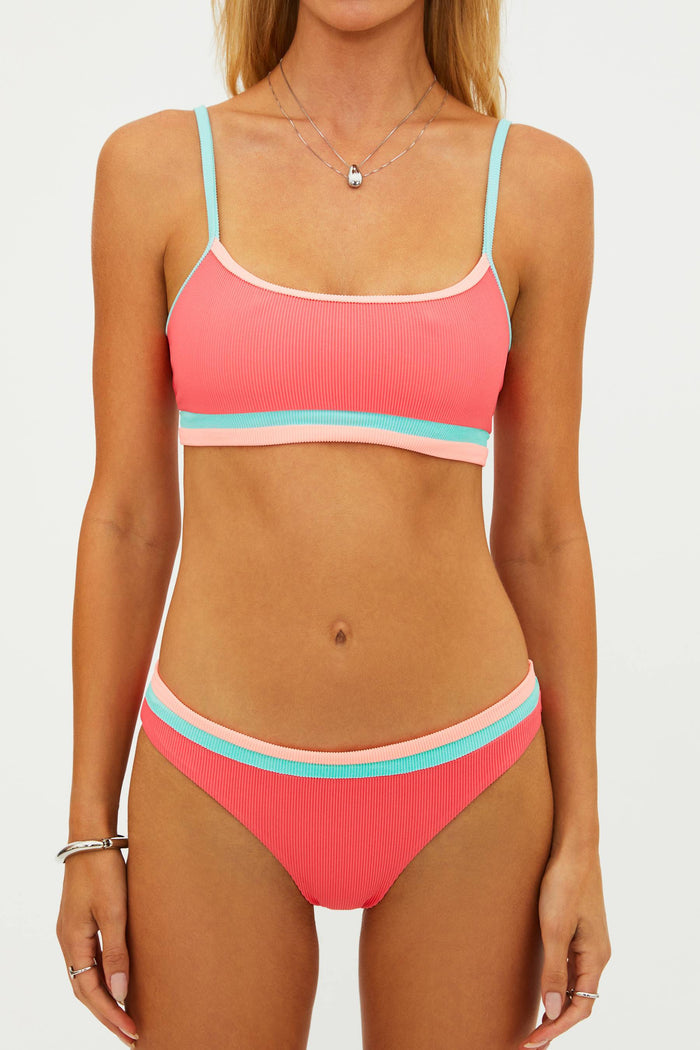 Woman wearing a pink and turquoise bikini set on a white background