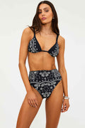 Woman wearing a black and white bandana print bikini on a white background