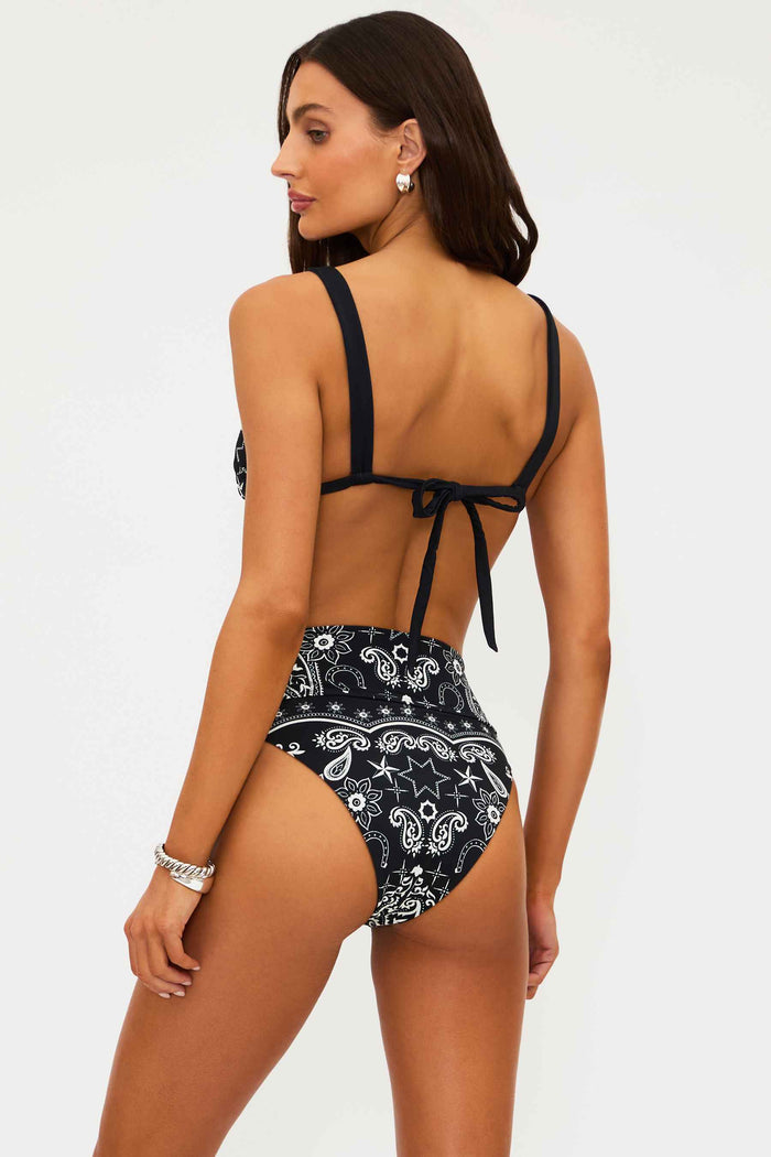 Woman wearing a black and white patterned bikini on a plain background