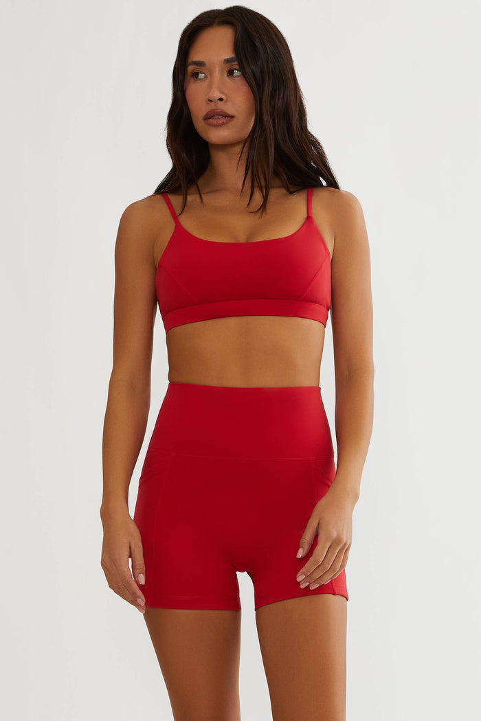 Woman wearing a red sports bra and shorts set on a white background