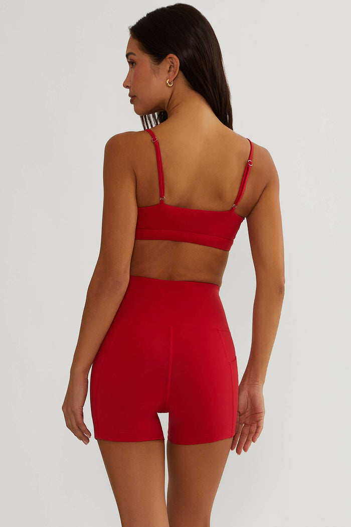 Woman wearing a red sports bra and shorts set on a white background