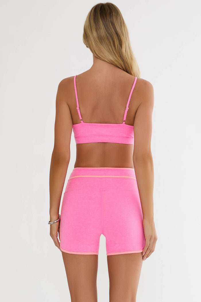Person wearing a pink sports bra and shorts set on a white background