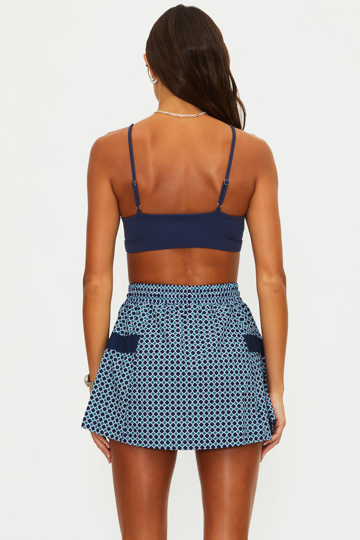 Woman wearing a blue patterned top and skirt on a white background