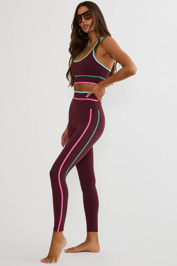 Woman wearing a sports bra and leggings with colorful stripes on a white background