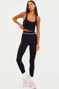 Woman wearing a black athletic outfit with pink accents on a white background