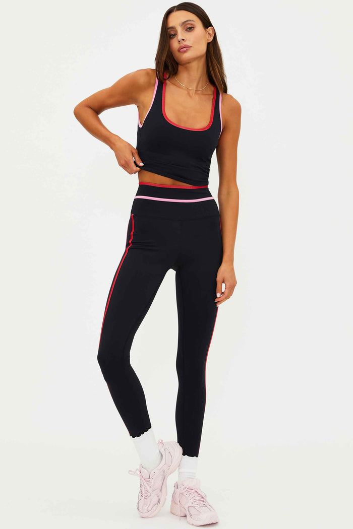Woman wearing a black athletic outfit with pink accents on a white background