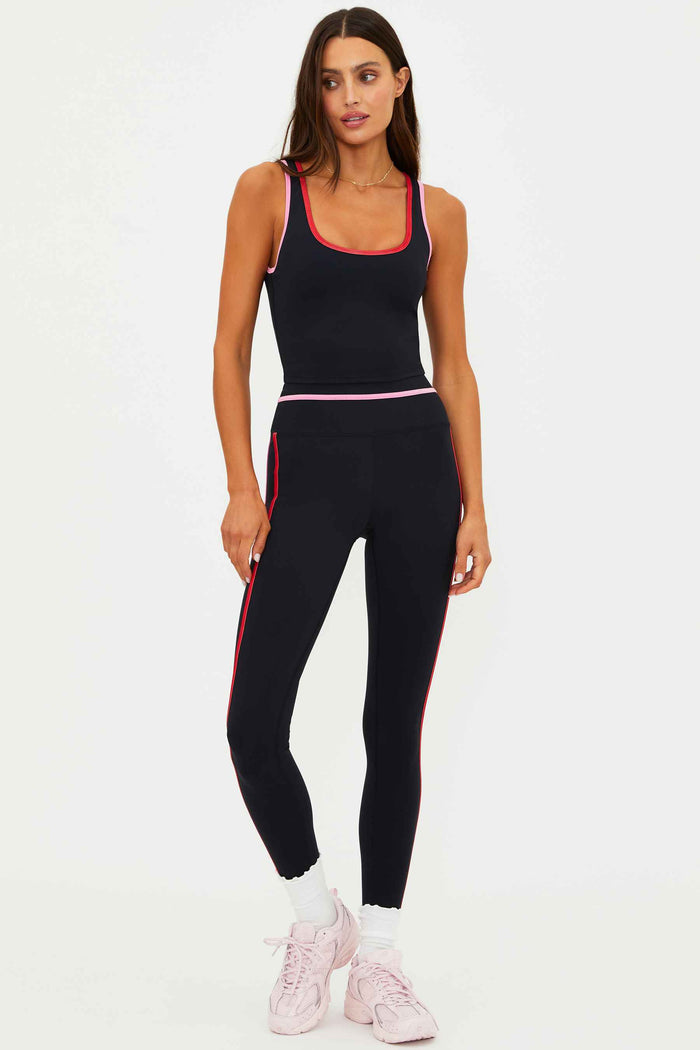 Woman wearing a black athletic outfit with red accents on a white background