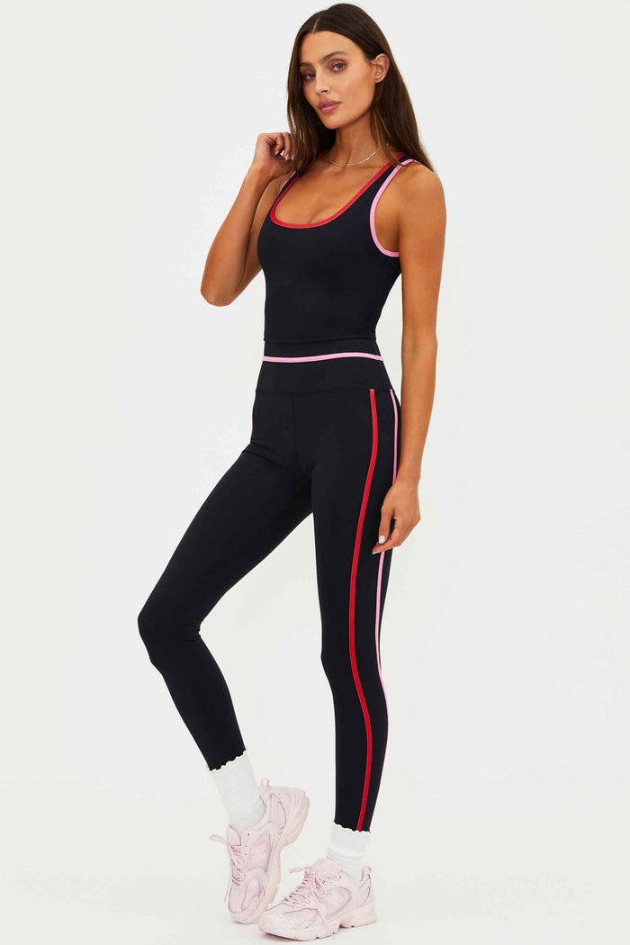 Woman wearing a black athletic outfit with red accents on a white background