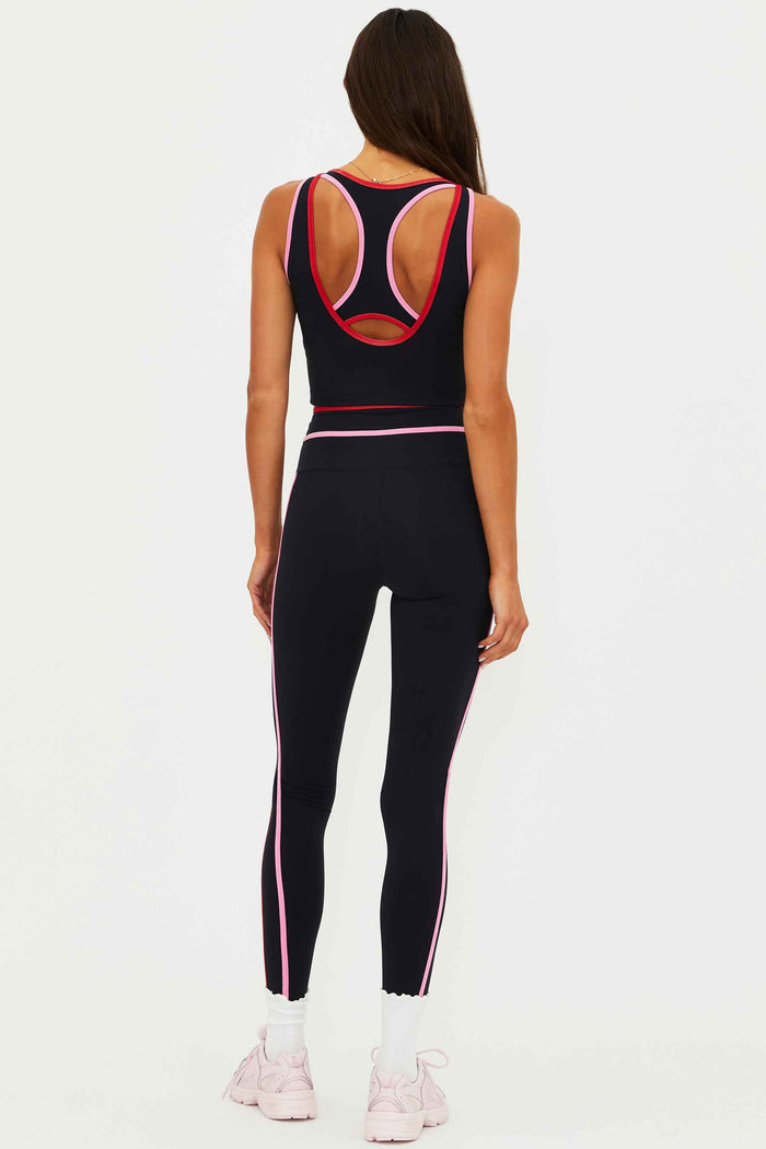 Person wearing a black athletic outfit with pink accents on a white background