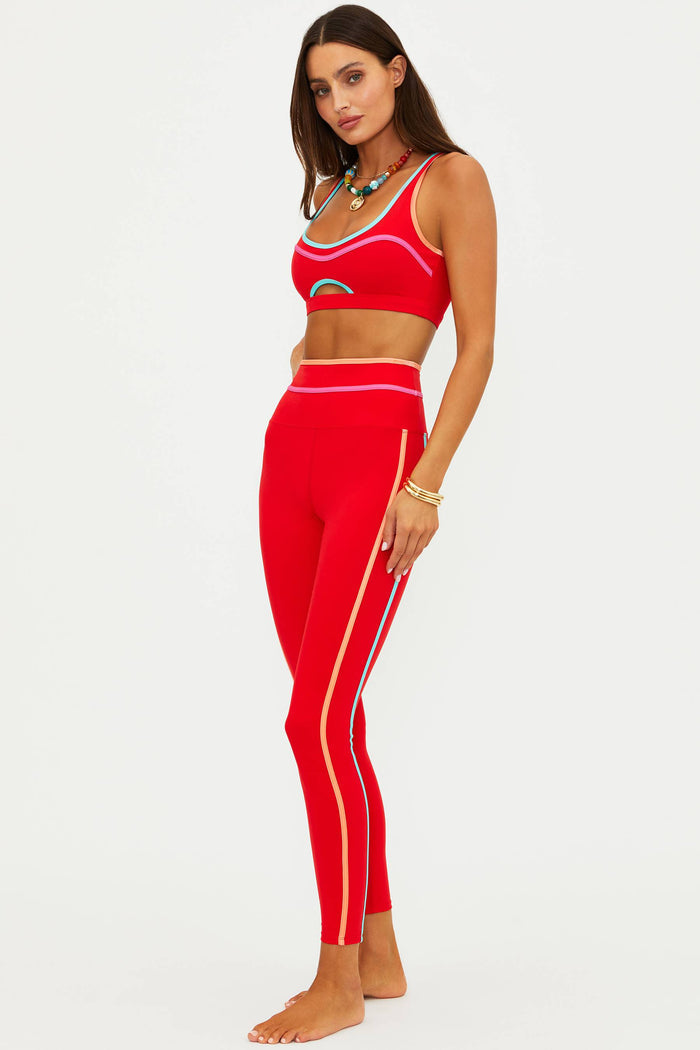 Woman wearing a red sports bra and leggings set on a white background