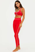 Woman wearing a red sports bra and leggings set on a white background