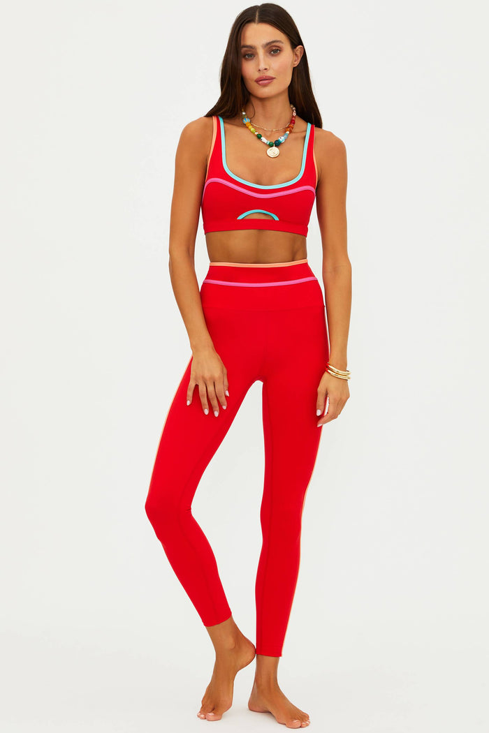 Woman wearing a red sports bra and leggings set on a white background