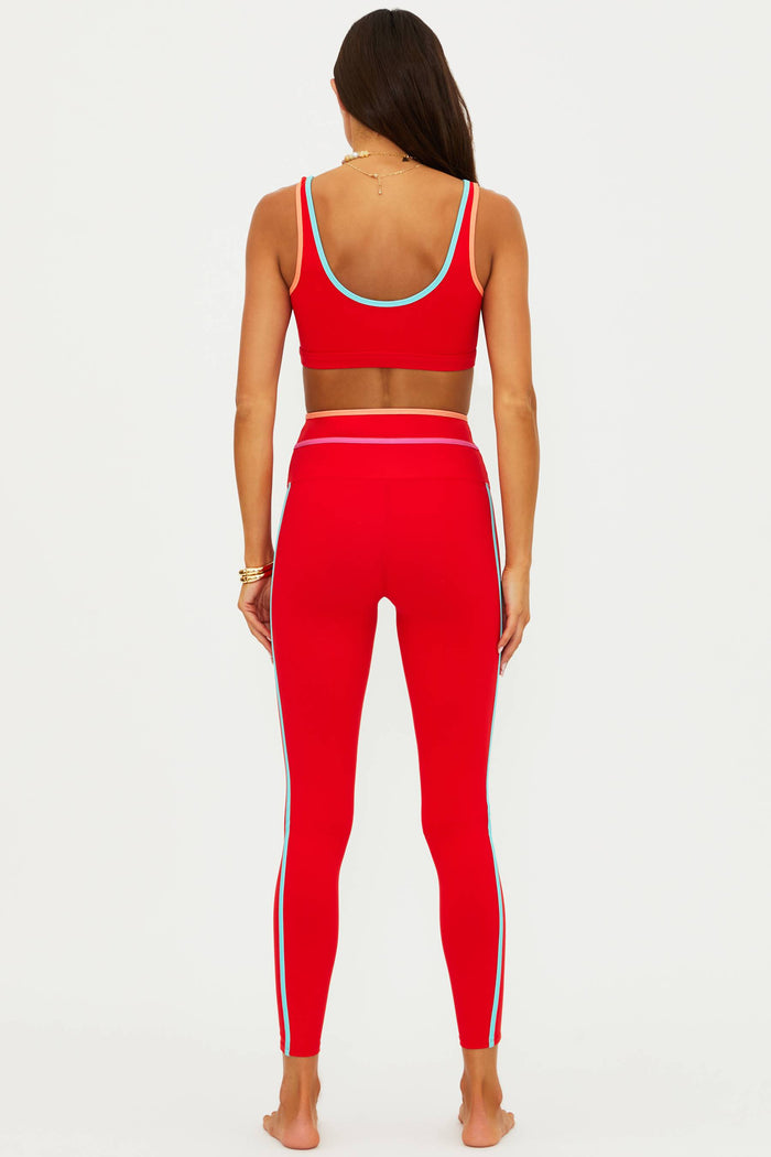 Person wearing a red sports bra and leggings set on a white background