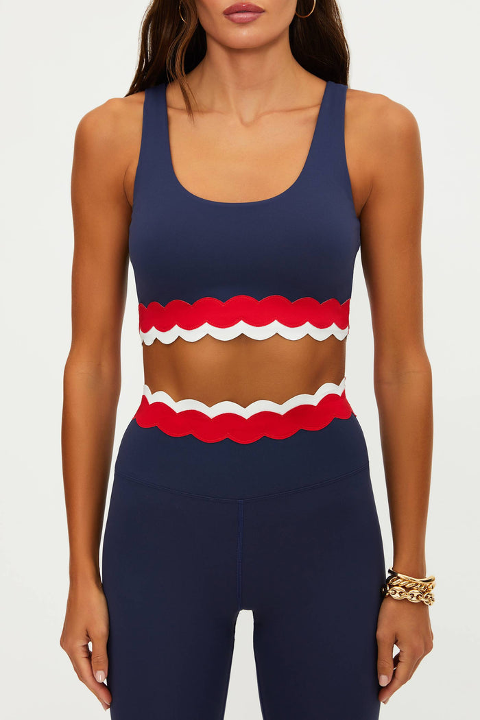 Navy blue sports bra with red and white ruffled design on a plain background
