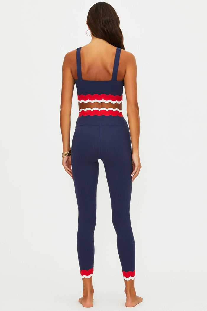 Woman wearing a navy blue jumpsuit with red and brown striped top on a white background