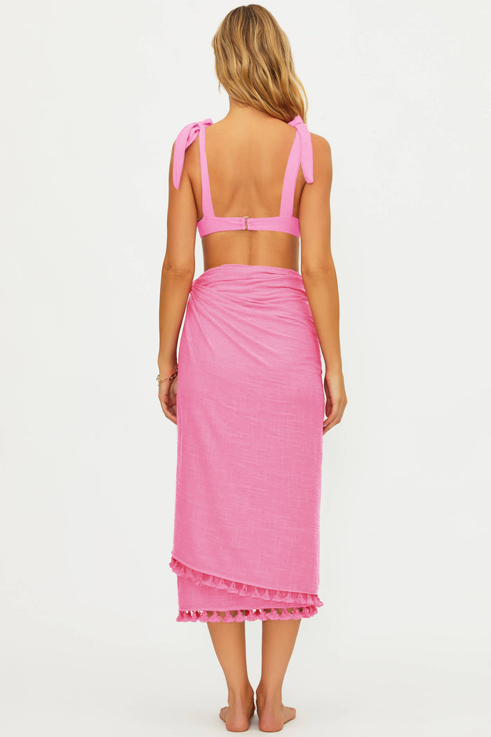 Woman wearing a pink bikini and matching sarong on a white background