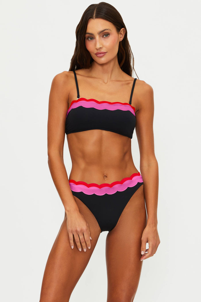 Woman wearing a black bikini with pink and red accents on a white background