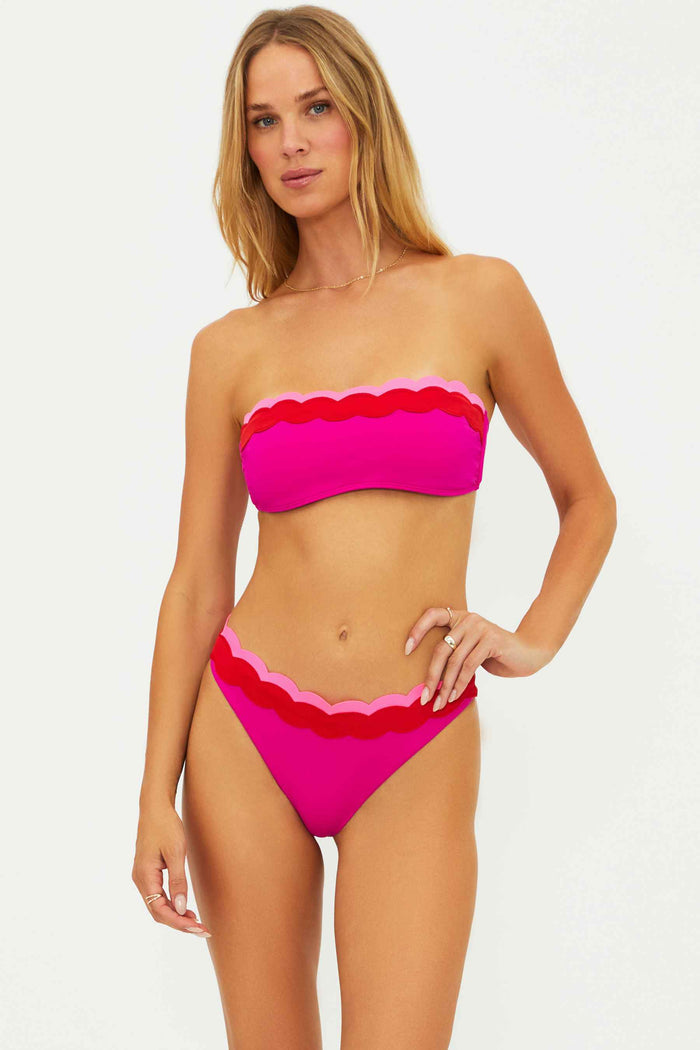 Woman wearing a pink bikini with scalloped edges on a white background