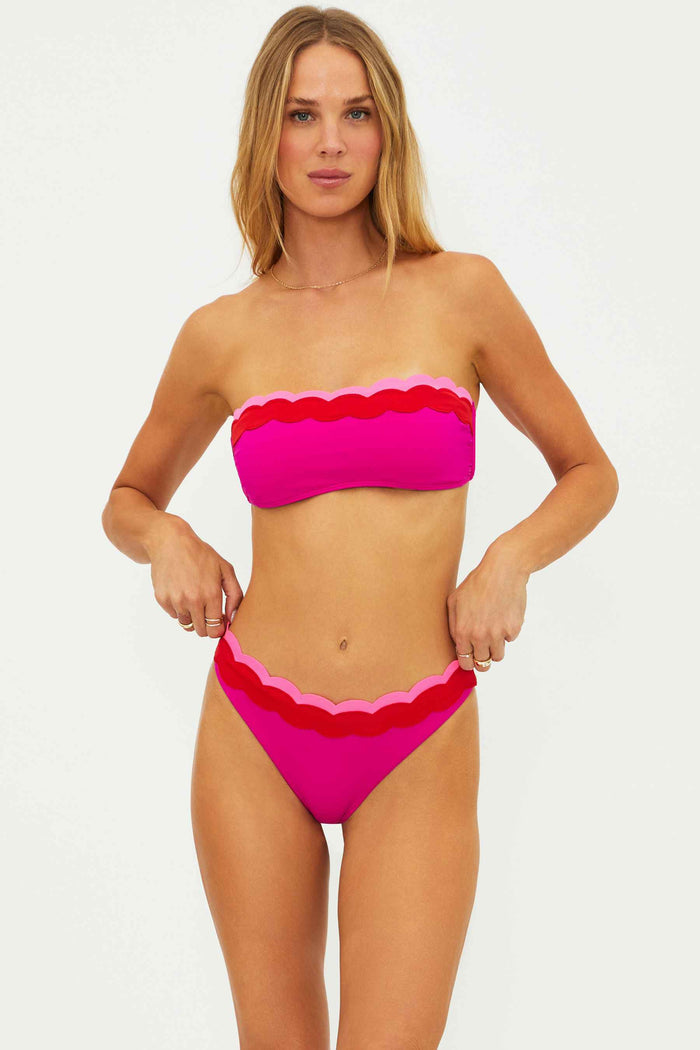 Woman wearing a pink bikini with scalloped edges on a white background