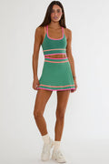 Woman wearing a green and pink dress with white sneakers on a white background