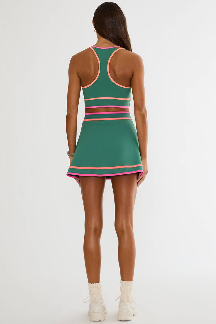 Green dress with pink accents worn by a person on a white background