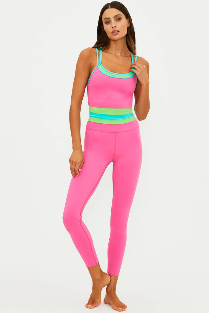 Woman wearing a pink athletic outfit with green accents on a white background