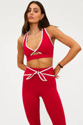 Woman wearing a red sports bra and leggings set on a white background