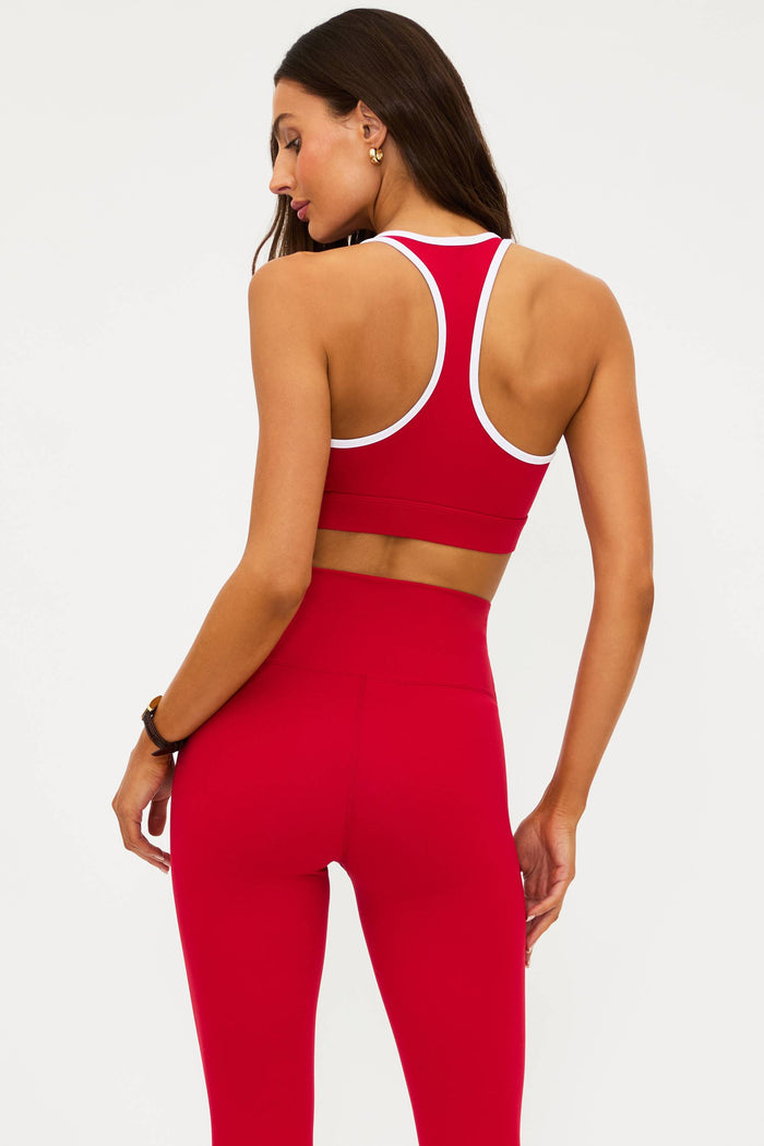 Person wearing a red sports bra and leggings set on a white background
