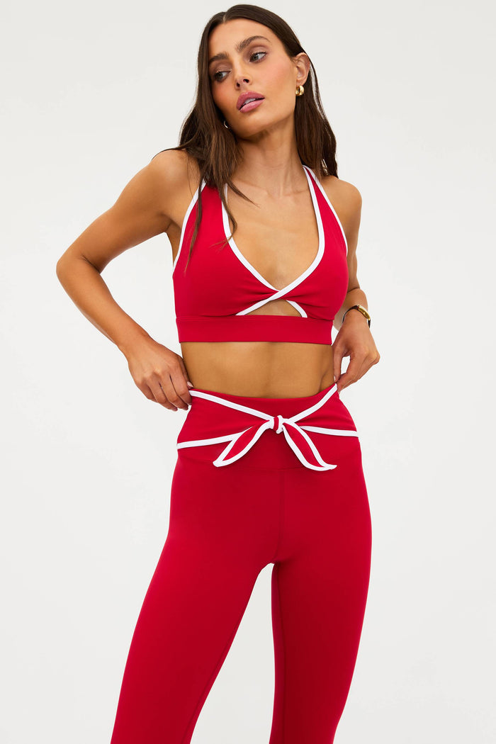 Woman wearing a red sports bra and leggings set on a white background