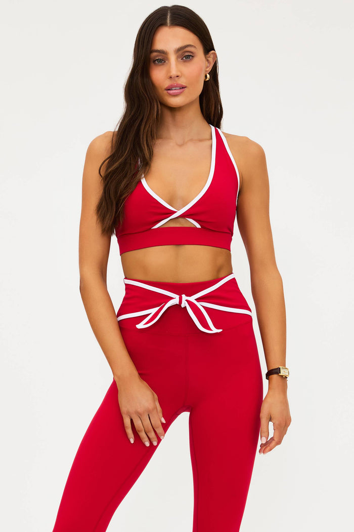 Woman wearing a red sports bra and leggings set on a white background