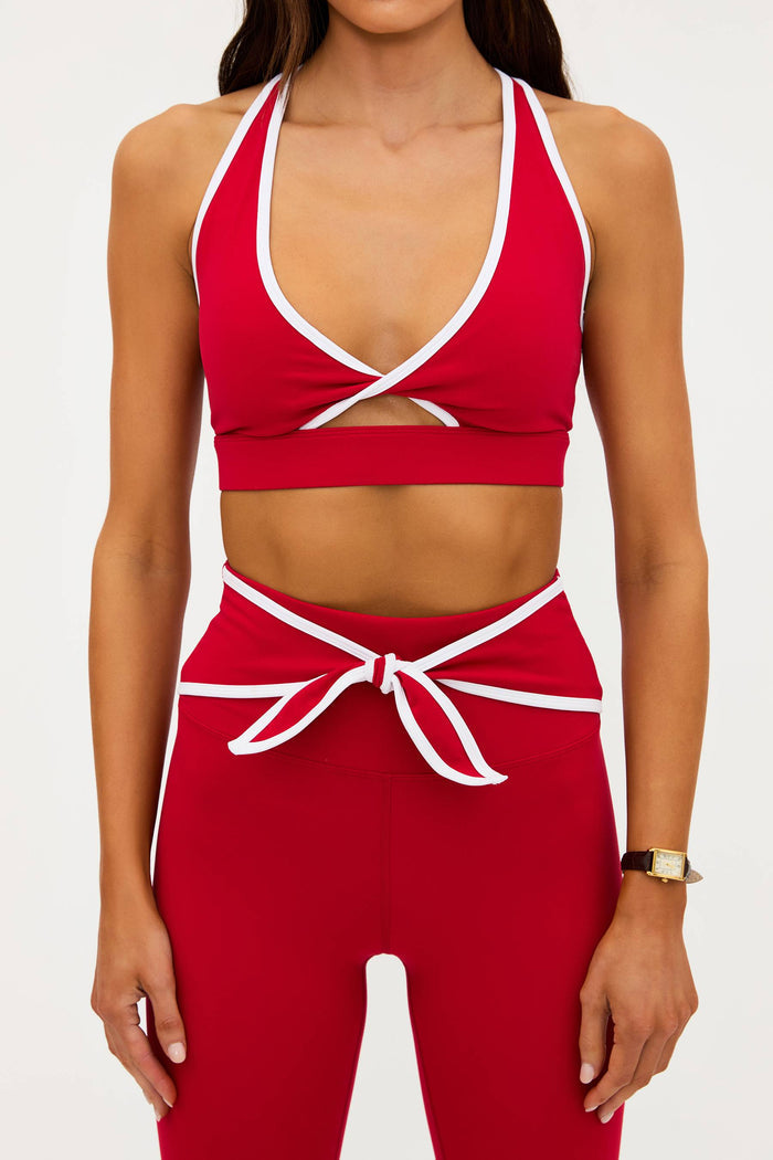 Red sports bra and leggings set with white accents on a plain background