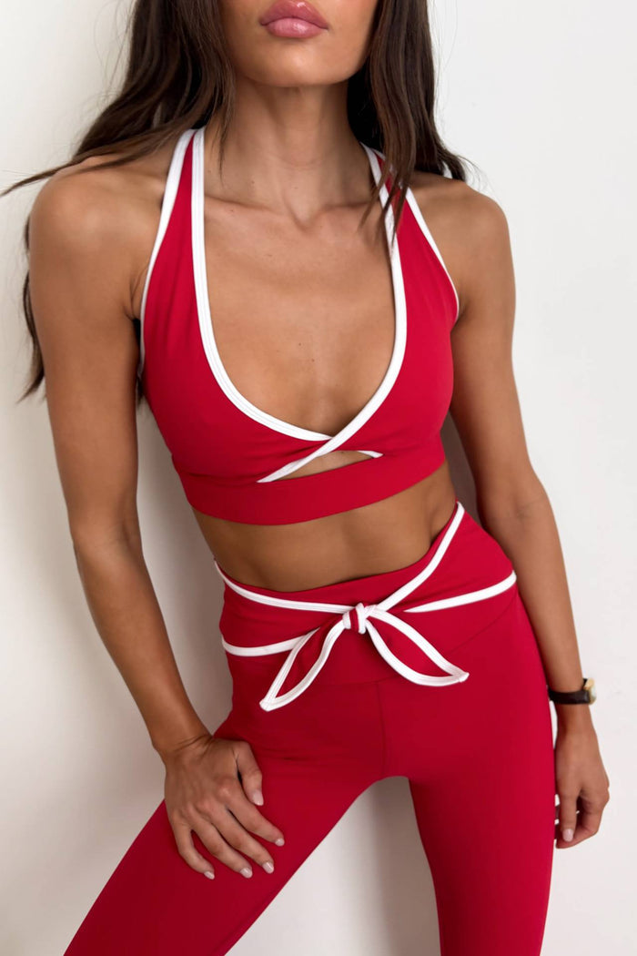 Red sports bra and leggings set with white accents on a plain background