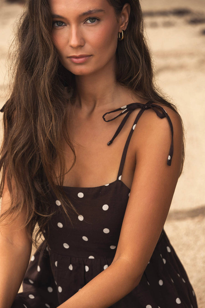 Woman wearing a black polka dot dress on a beach