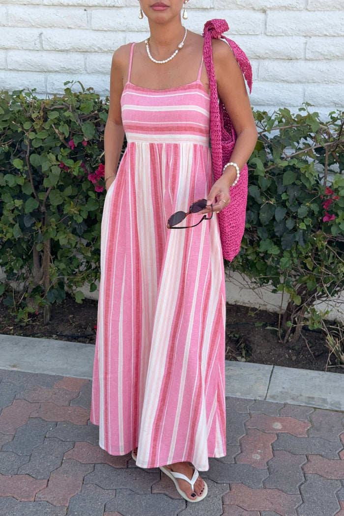 Woman wearing a pink and white striped dress holding a pink bag.