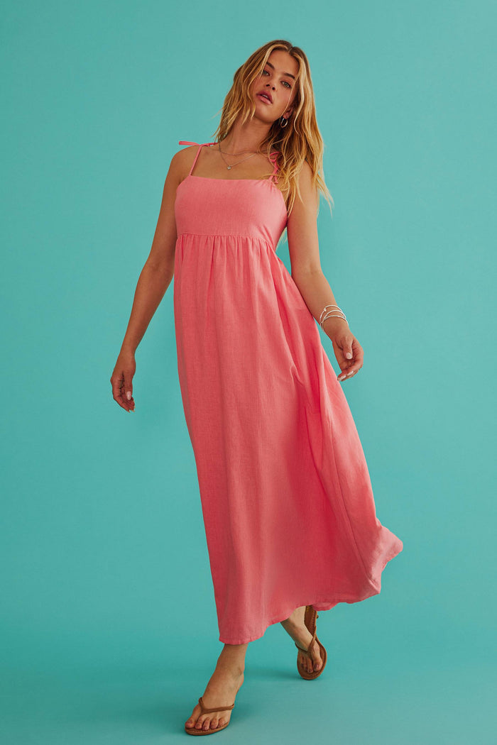 Woman wearing a pink dress against a teal background