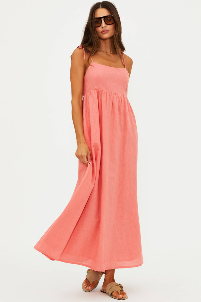 Woman wearing a coral pink dress on a white background