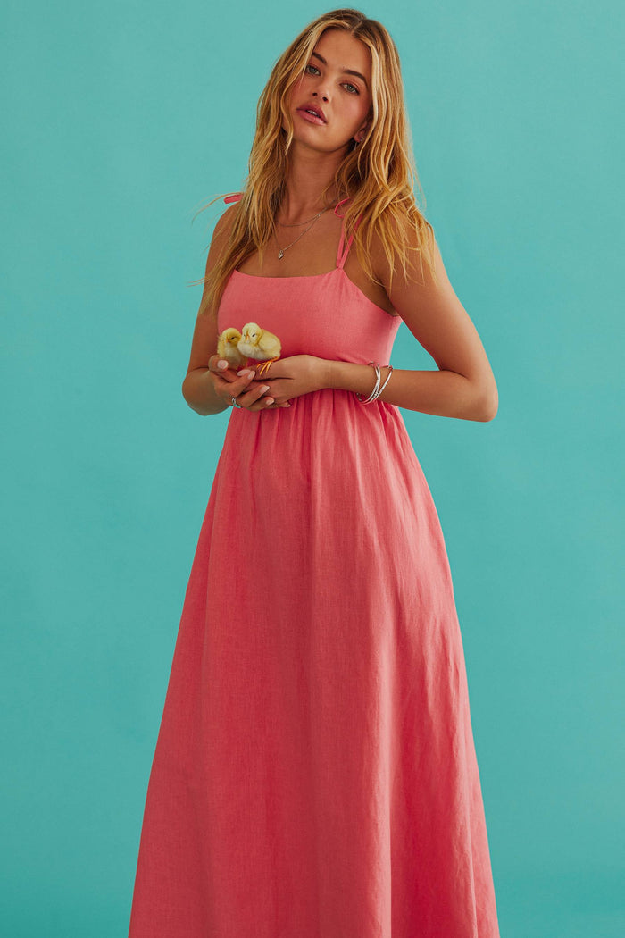 Woman wearing a pink dress against a teal background