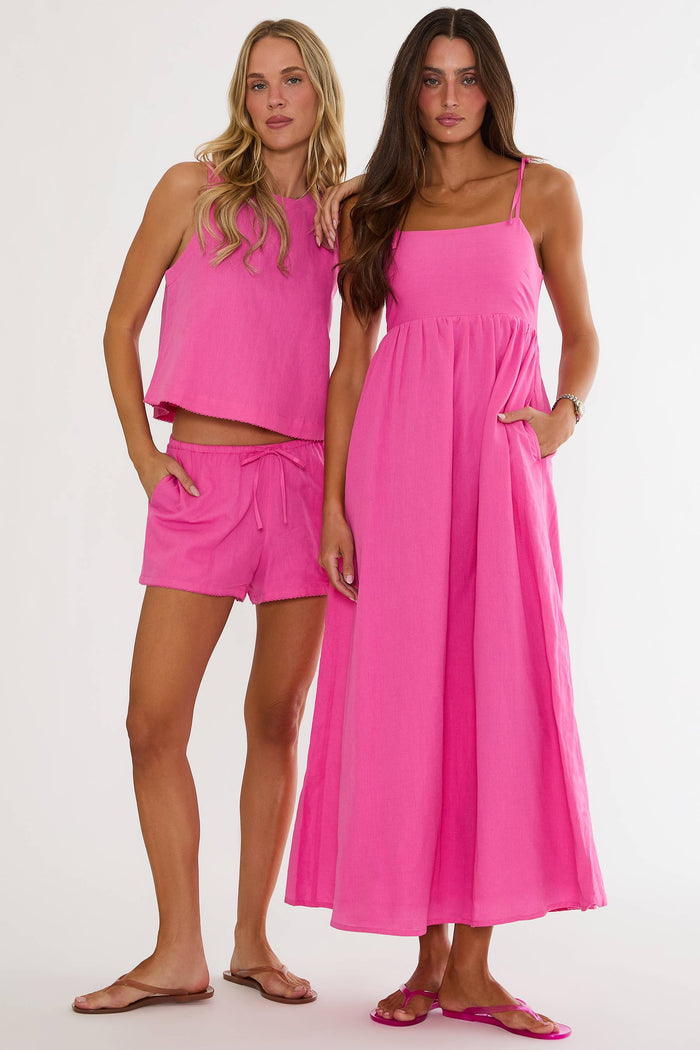 Two women wearing pink outfits on a white background