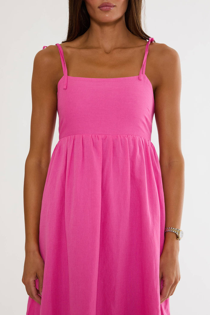 Pink dress with thin straps worn by a model on a white background