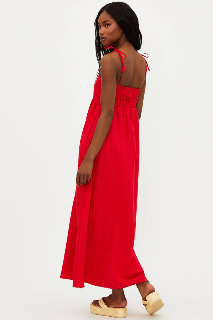 A model wearing a red maxi dress with tie shoulder straps and side pockets.