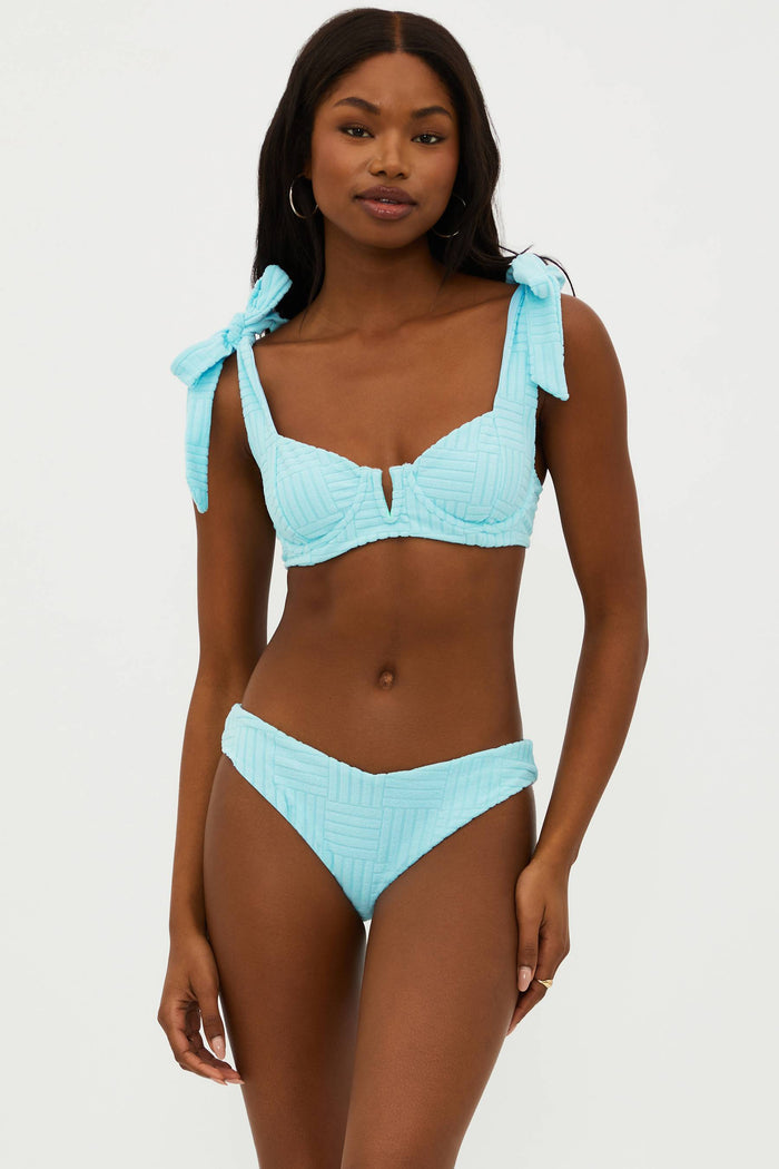 This image features the "Vanessa Bottom Blueberry Ice Terry," a stylish and comfortable swimwear bottom. Modelled by a woman, the bottoms are showcased in a striking shade of summer blue.