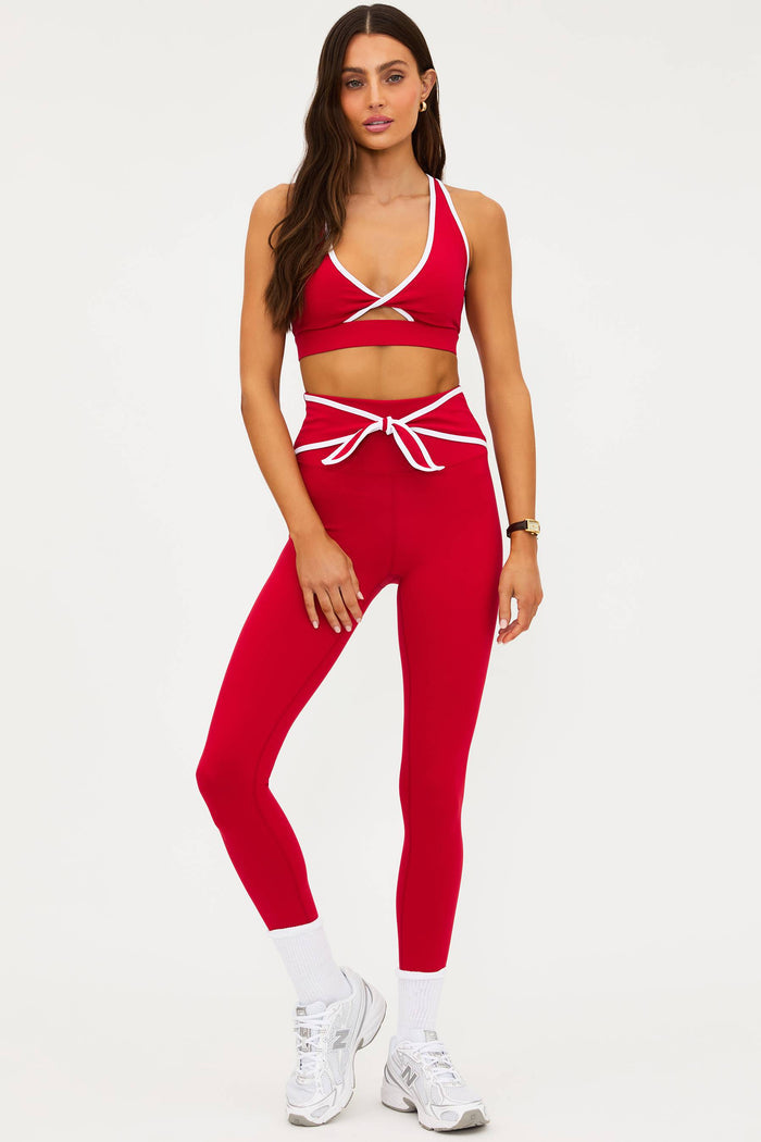 Woman wearing a red sports bra and leggings set on a white background