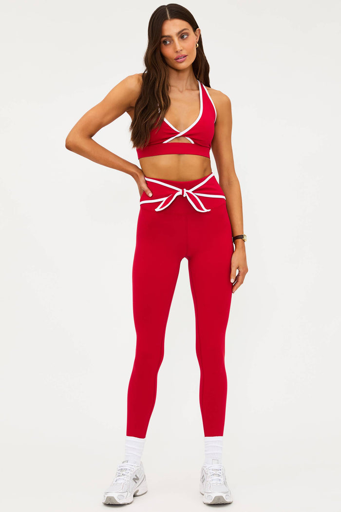 Woman wearing a red sports bra and leggings set on a white background