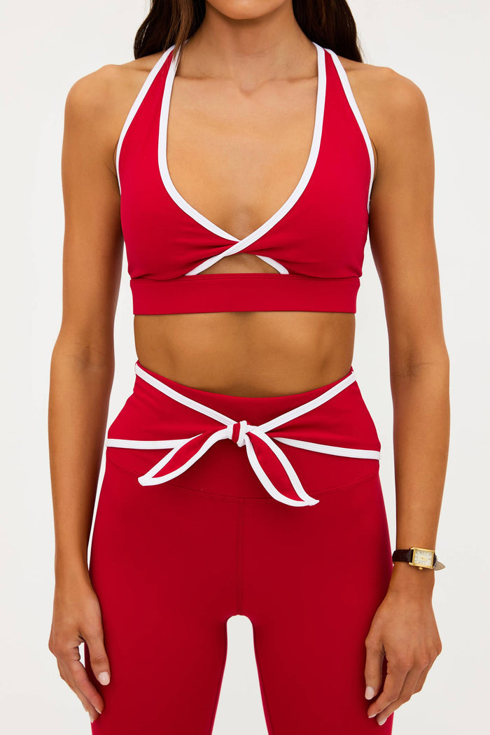 Red sports bra and leggings set with white accents on a plain background